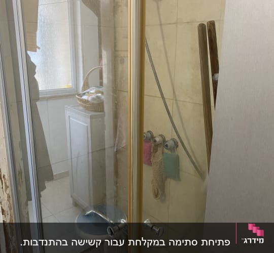 תא מקלחון זכוכית וברז מקלחת בחדר רחצה